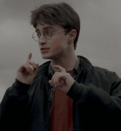 a young man wearing glasses and a black jacket is pointing his finger up .